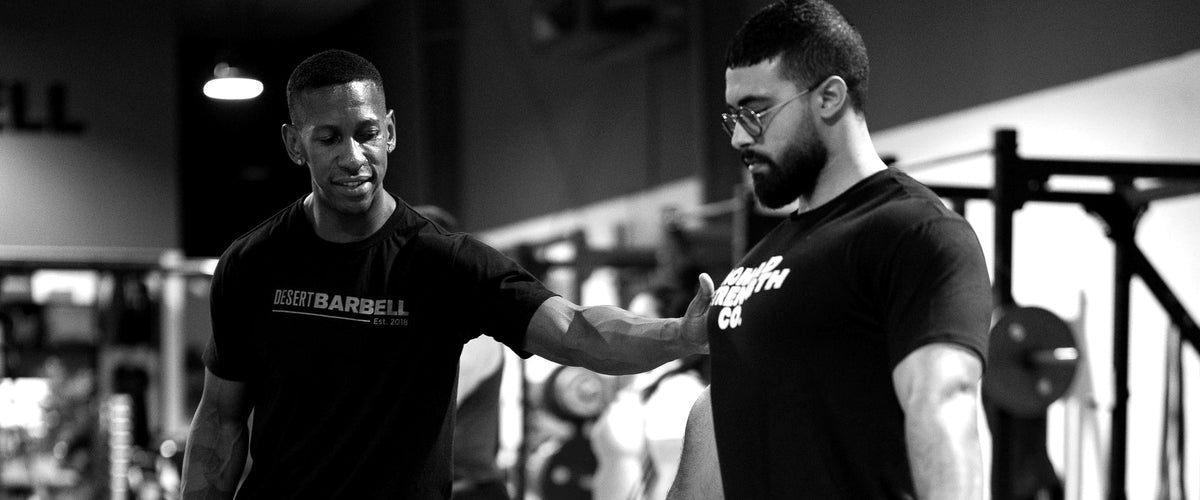 Personal trainer coaching a lifter through a barbell set at Desert Barbell Dubai